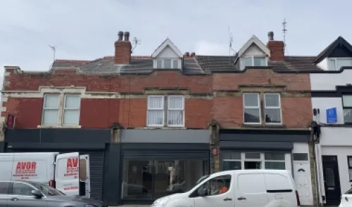 Red brick commercial property with vacant storefront and upstairs apartments.
