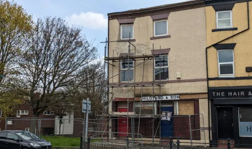 Hildyard & Son" building with scaffolding and boarded-up storefront undergoing renovations.