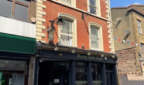 Room forty four" bar exterior with dark facade and red brick upper floors.
