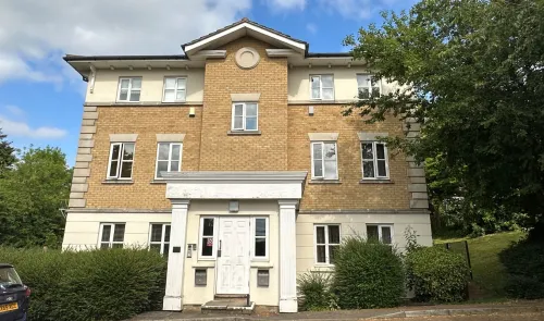 Modern tan brick apartment building with white entryway and columns.