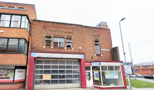 Vacant brick commercial building with garage door and storefront windows.