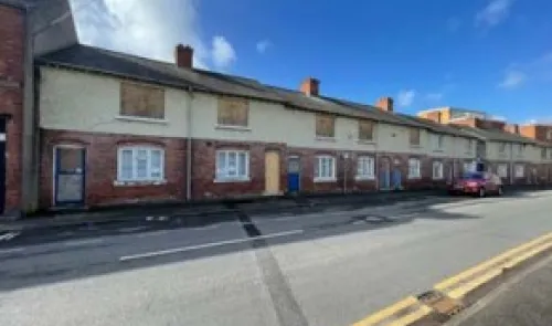 Row of brick terraced houses with boarded-up windows.