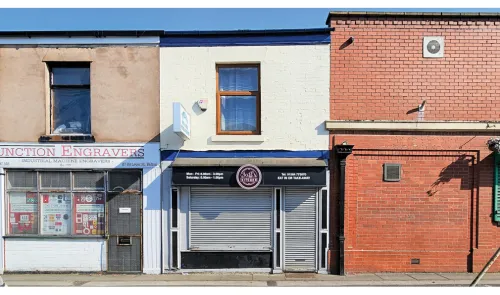 Saff's Kitchen" storefront between other businesses on a sunny day. Metal security gate closed.