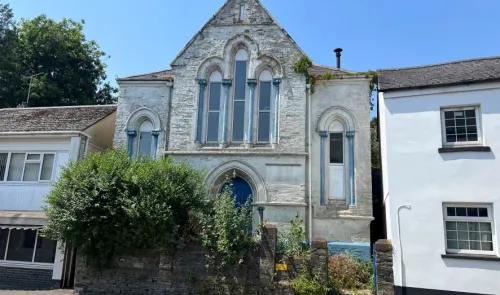 White stone chapel with blue architectural details and arched windows.