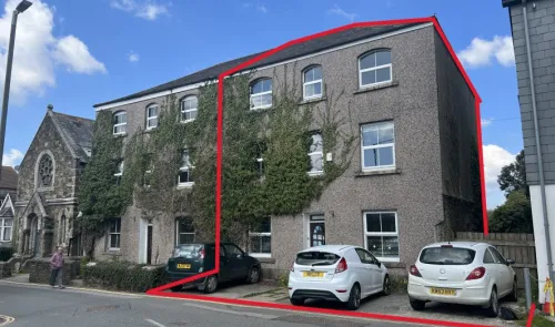 Ivy-covered commercial property exterior with arched windows and parking spaces.