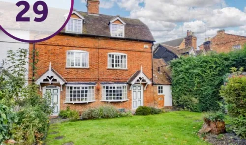 Charming red brick house (Lot 29) with green lawn and white trim.