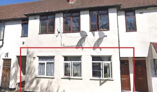 Exterior of a white semi-detached house with multiple windows and satellite dishes.