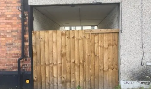 Wooden fence gate under a building overhang.