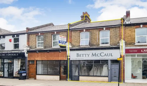 Brick two-story commercial building with "Betty McCaul" storefront and adjacent "To Let" unit.