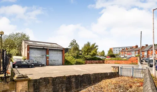 Commercial property with gated parking, garage doors, and brick retaining wall.