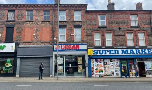 Brick buildings with "Urban Chicken & Pizza" and "Supermarket" storefronts.