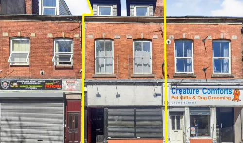 Red brick commercial property with two-story dormer windows and ground-floor storefront.