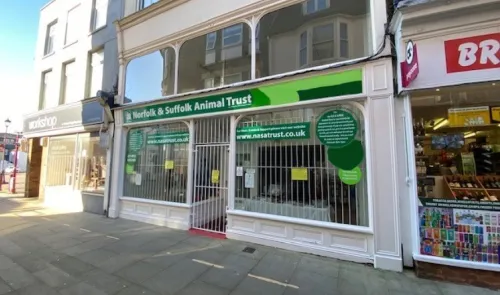 Norfolk & Suffolk Animal Trust storefront with security gate and website address displayed.