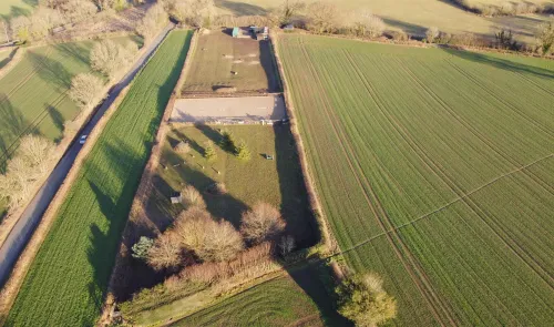 Aerial view of a horse arena, fields, and a road.