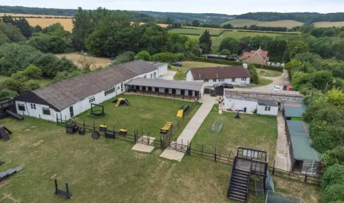 Aerial view of dog kennels, training area, and outbuildings in a rural setting.