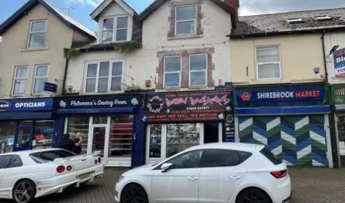 Storefront view of various shops, including "Philomena's Sewing Room" and "Shirebrook Market.