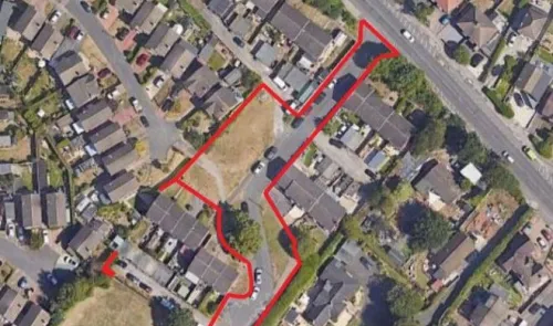 Aerial view of land outlined in red, amidst residential houses and roads.