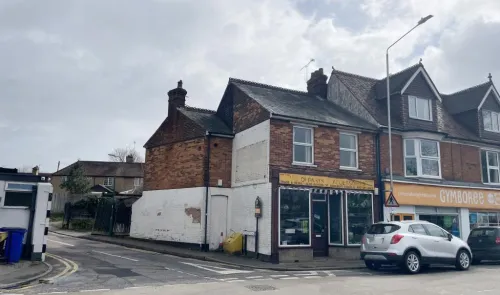 Brick retail building with "D. DAVIS ACCESSORIES" signage, street view, parked car.