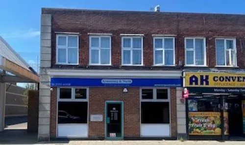 Two-story brick building with "Armstrong & North" signage, ground floor storefront, and adjacent businesses.