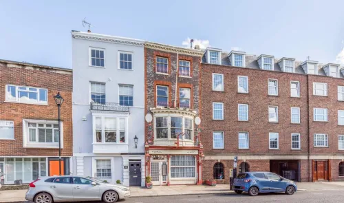 Charming historic storefront with bay window between two residential buildings on a city street.