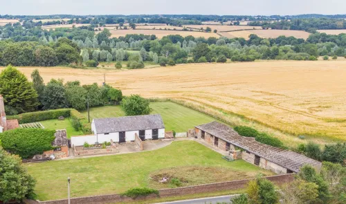 Aerial view of farm buildings, grassy yards, and golden crop fields.