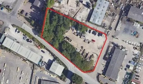 Aerial view of commercial land with red outline, trees, and equipment.