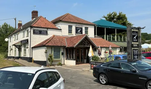 The Gull Inn, a white and terracotta pub, with cars parked outside and a covered patio area.