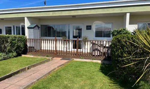 Red brick bungalow with bay window and green front lawn.