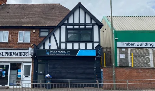 Daily Mobility" storefront with black shutters between a supermarket and timber building.