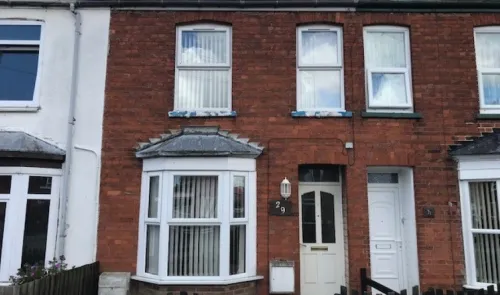 Red brick terraced house with white bay window and front door, number 29.