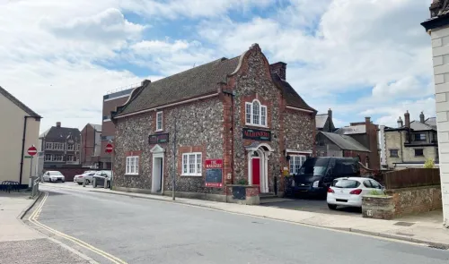 The Mariners" pub, a stone building with a red door, on a street corner.
