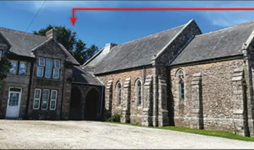 Stone house and attached chapel with arched windows and slate roof.