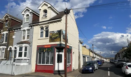 Corner shop with "Model Centre" sign and steam train mural, residential street view.