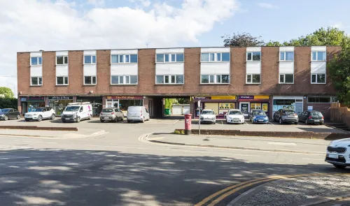 Brick two-story building with retail units on ground floor, including "The Pet Shop" and "Premier" convenience store. Cars pa