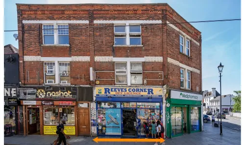 Reeves Corner" off-licence shopfront between other businesses on a UK high street.