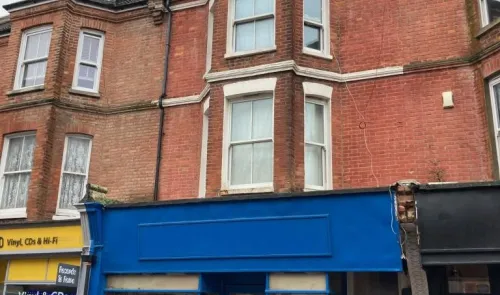 Red brick building with bright blue shop front and white-framed windows. A "Vinyl & CDs" shop is visible next door.