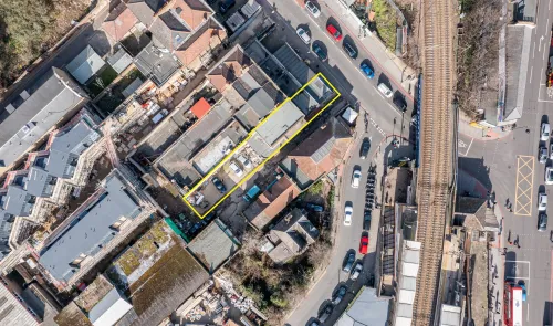 Aerial view of a highlighted property, adjacent to a railway line and surrounded by urban development.