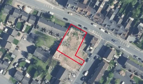 Aerial view of vacant land outlined in red, surrounded by residential properties and a road.