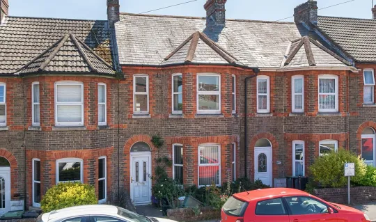 exterior of a mid terrace brick built house with white front door 
