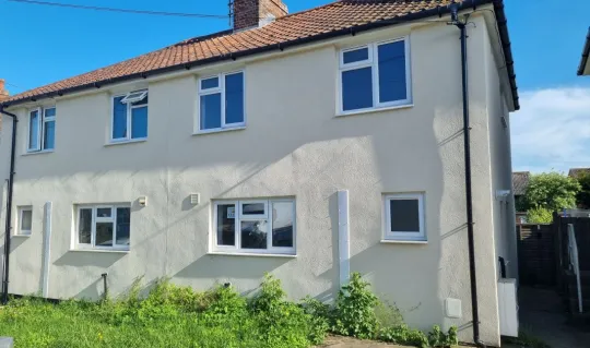 exterior of cream coloured two storey house with green grass front garden